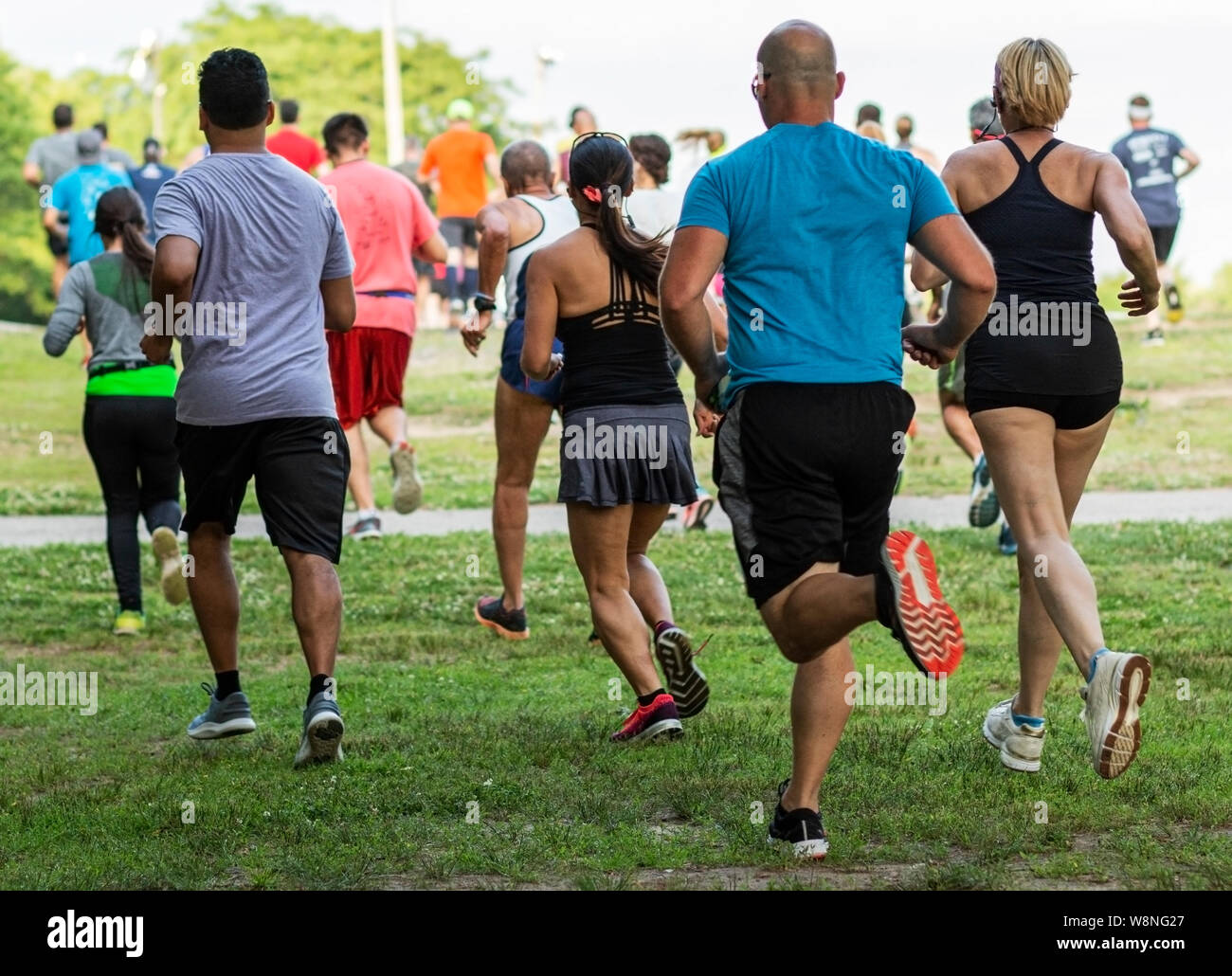 Runners running on grass away from the camera during a 10K summer