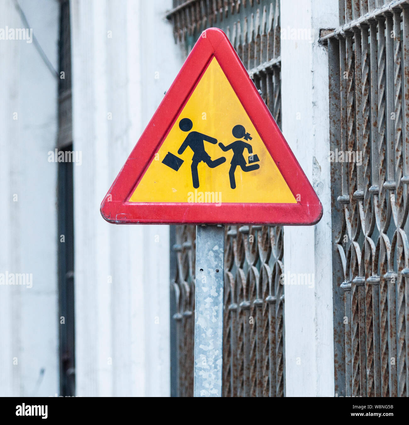 A red and yellow sign with a picture of an adult helping a child across the street. Stock Photo