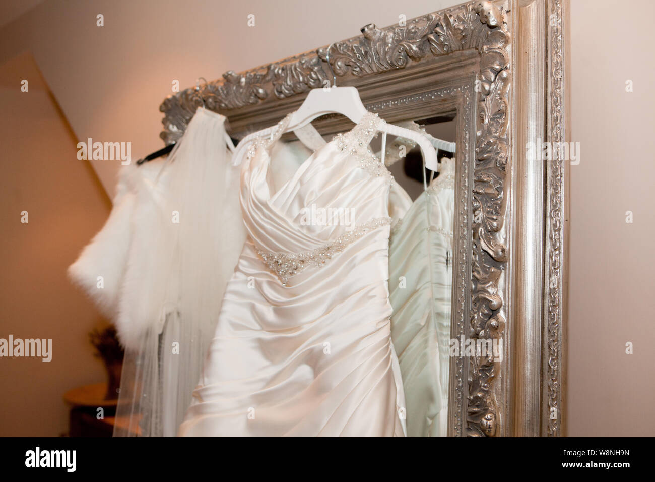 Vintage Style Wedding Dress Hanging On Silver Framed Mirror Stock