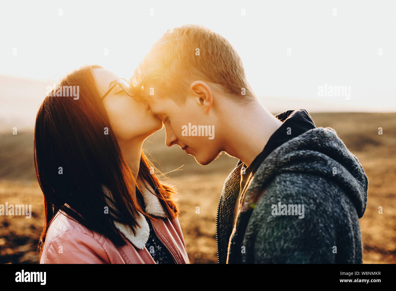 Side view of cute young female kissing handsome guy in forehead ...