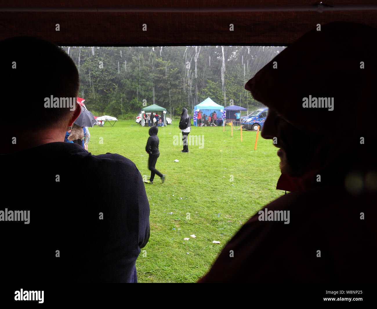 Annual Event rained off - A lone figure refuses to be dissuaded from watching a stage event at a festival as  all other onlookers rush for shelter from a torrential downpour Stock Photo