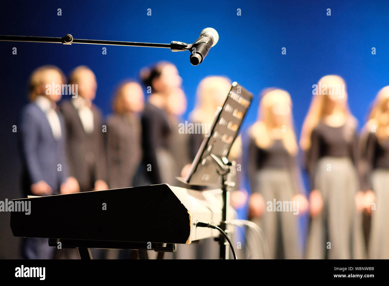 Microphone and music stand in front of electric pianos on the stage of