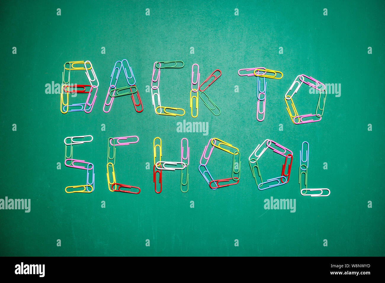 Background with the words back to school written with multicolored paper clips on green chalkboard. Back to school concept. Stock Photo