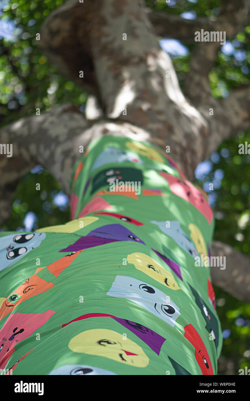 Tree trunk covered with different coloured and shaped faces at the Southbank Stock Photo