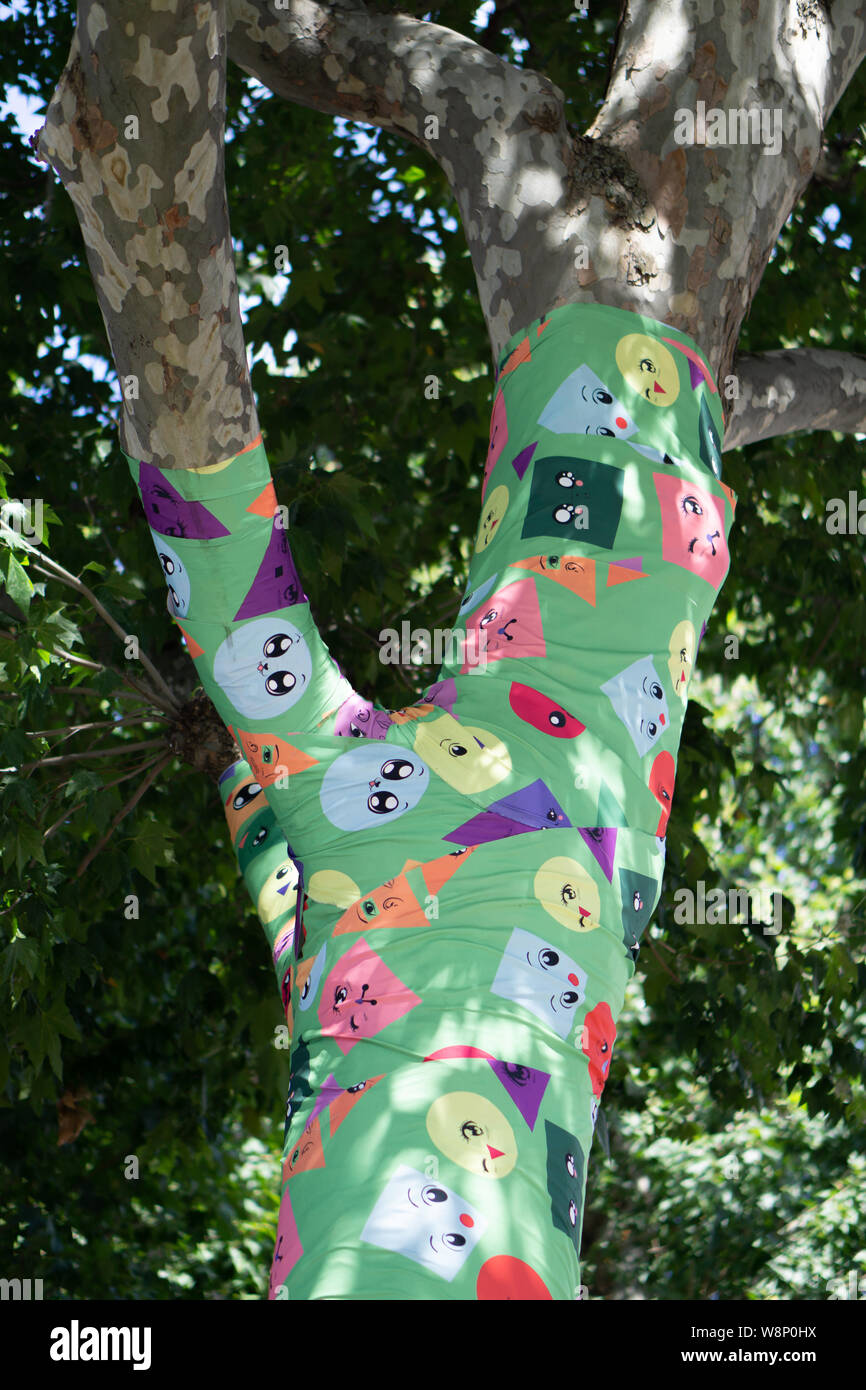Tree trunk covered with different coloured and shaped faces at the Southbank Stock Photo