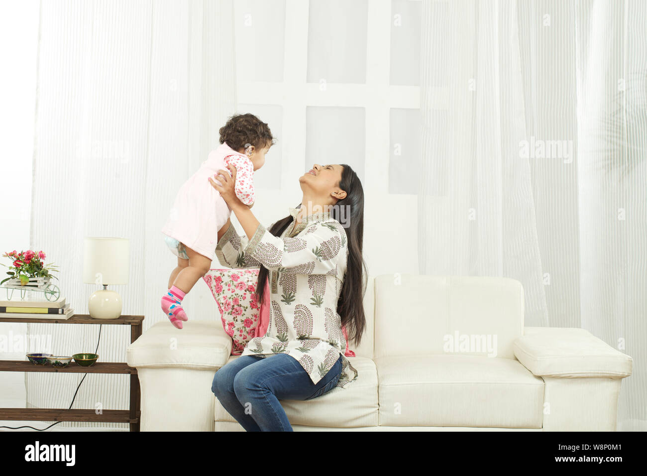 Mother suffering from lower back pain while picking up baby Stock Photo