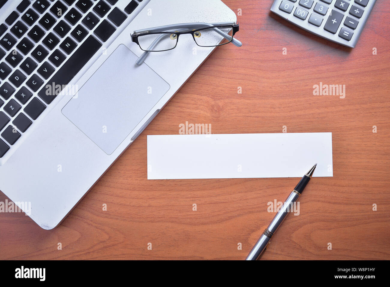 Laptop with blank white label and pen on wooden table Stock Photo