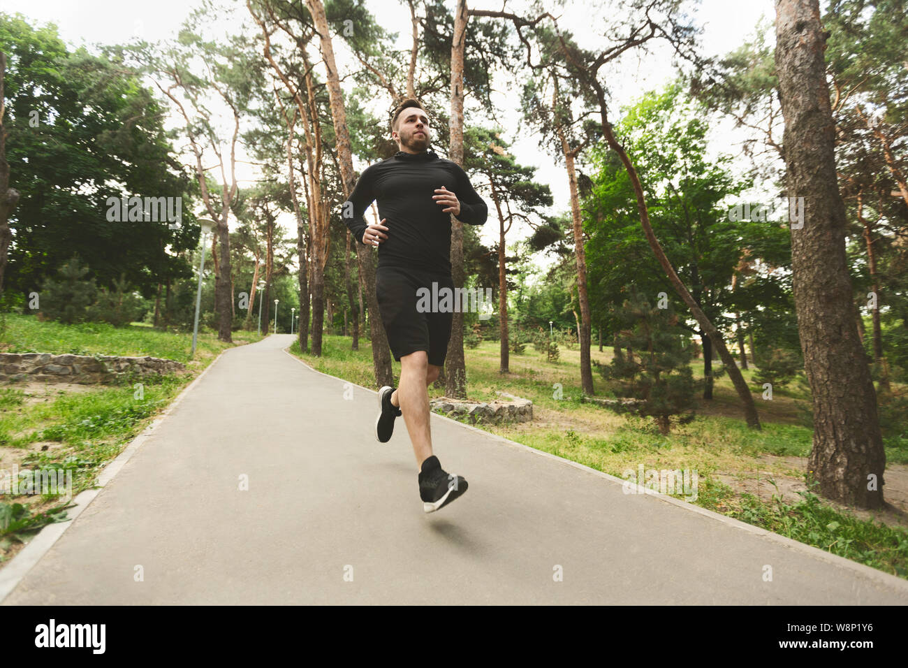 Sporty man jogging in park during morning workout Stock Photo