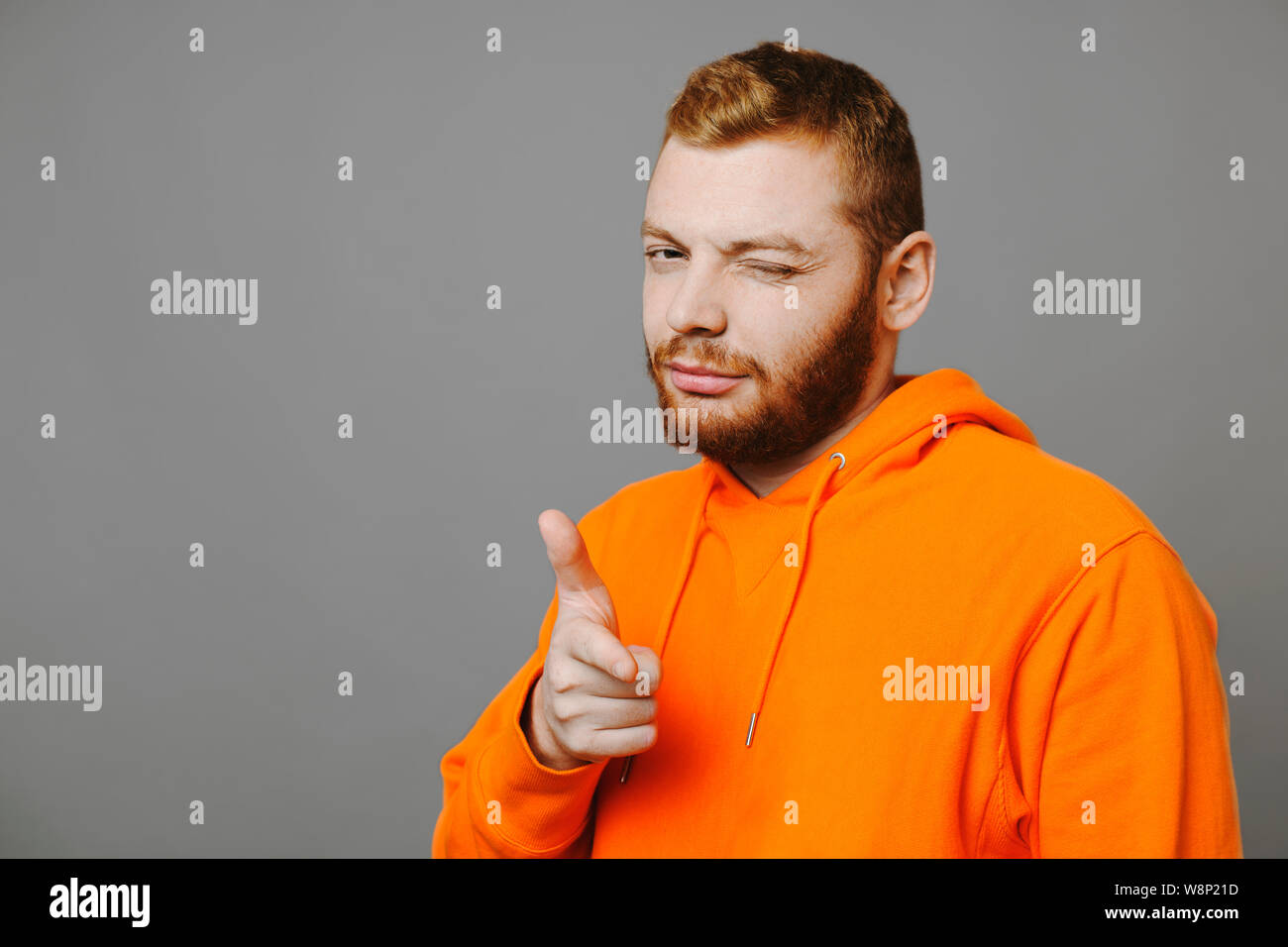 Handsome Guy In Orange Hoodie Winking And Pointing At Camera While