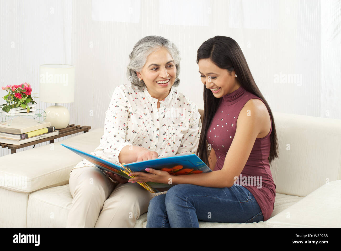 Old woman with her daughter looking at family photo album Stock Photo ...