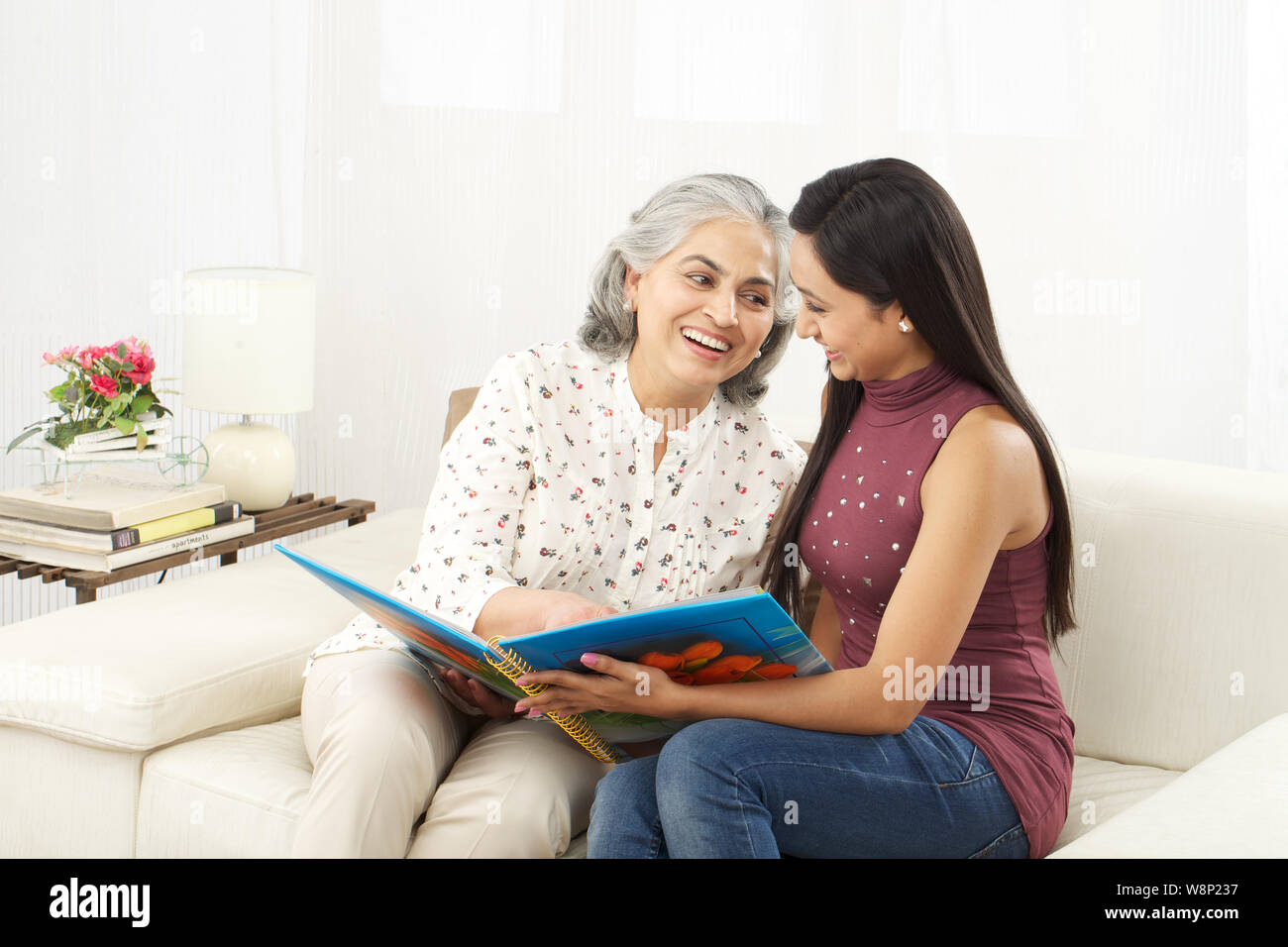 Old woman with her daughter looking at family photo album Stock Photo ...