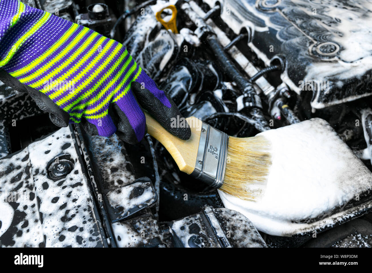 A man cleaning car engine with shampoo and brush. Car detailing or valeting concept. Selective focus. Car detailing. Cleaning with sponge. Worker clea Stock Photo