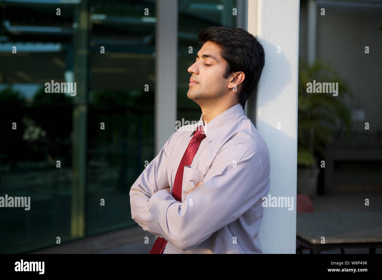 Businessman leaning against pole Stock Photo