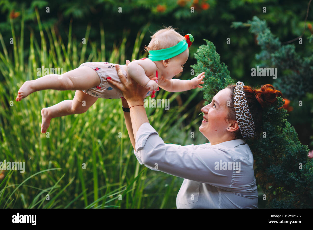happy harmonious family outdoors. mother throws baby up, laughing and
