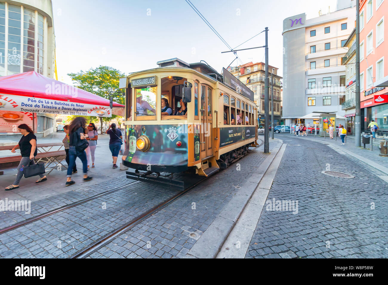 An old typical tramway is riding on railroad in centre direction. Famous vintage tram on street of Old Town, Porto, Stock Photo