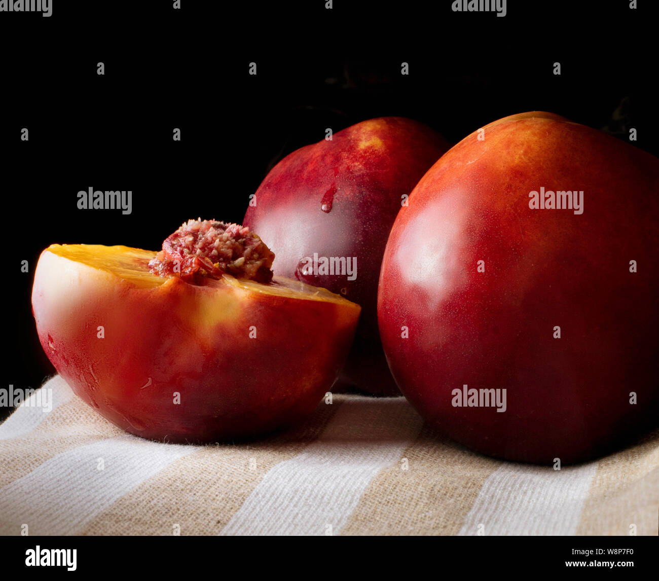 Two and a half peaches on a linen cloth. Peach seed. Fruit for