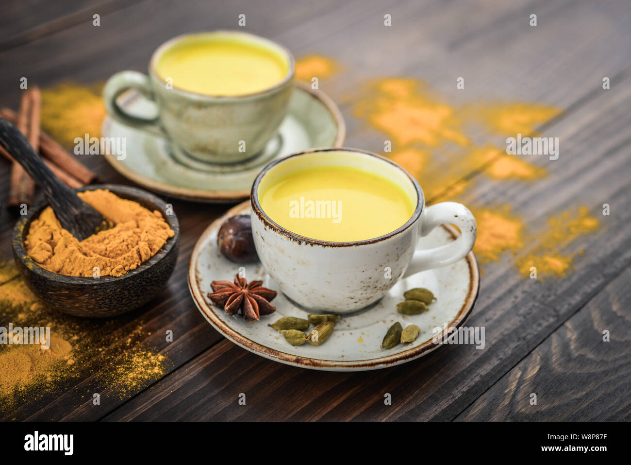Traditional Indian drink turmeric milk is golden milk with cinnamon, cloves, pepper and turmeric on a wooden background with spices Stock Photo