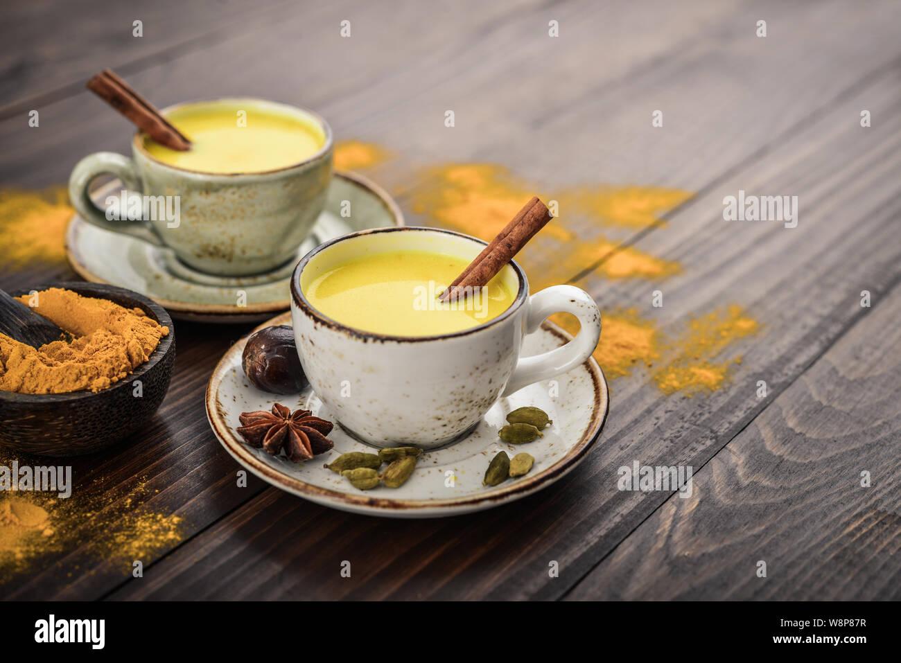 Traditional Indian drink turmeric milk is golden milk with cinnamon, cloves, pepper and turmeric on a wooden background with spices Stock Photo