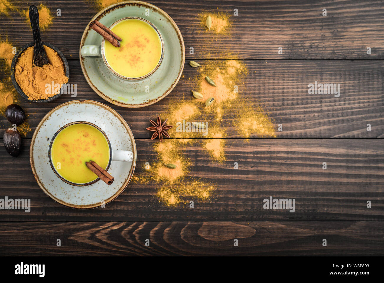 Traditional Indian drink turmeric milk is golden milk with cinnamon, cloves, pepper and turmeric on a wooden background with spices, top view Stock Photo