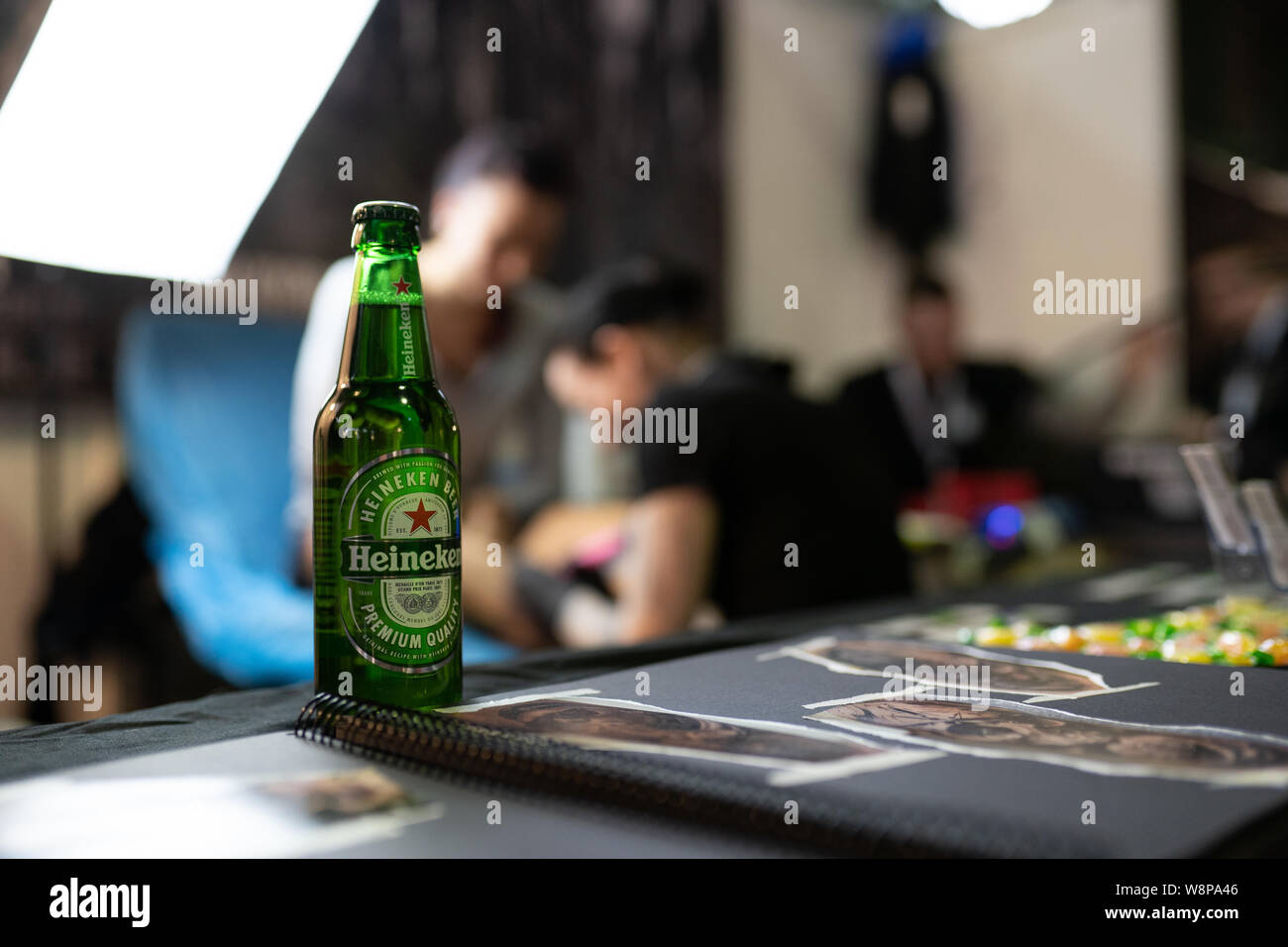 Leipzig saxonia germany february 02 2019: Tattoo convention: bottle heineken beer in front of a tattooing inking people. Stock Photo