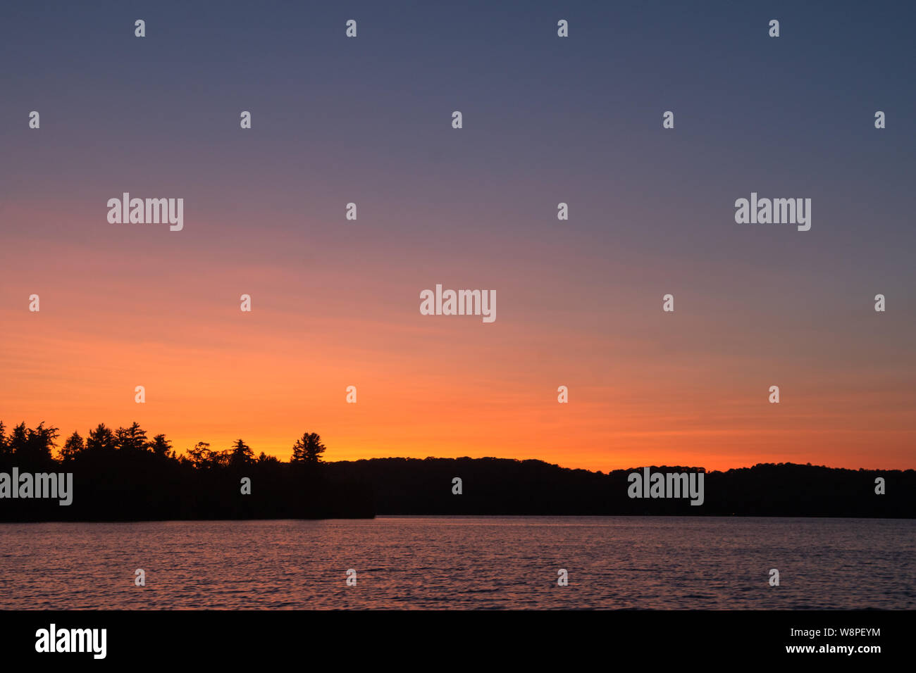 Silhouette of a Forested horizon under an afterglow after fading  sunset in the expansive blue coral northern sky in Haliburton Ontario Canada. Stock Photo