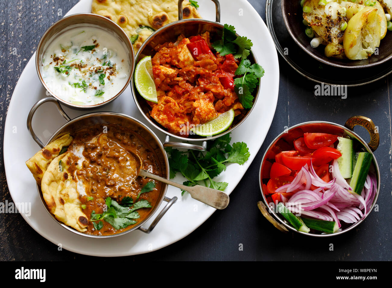 Indian curry meal with black lentils dal, spicy potatoes, rice, naan bread and raita Stock Photo