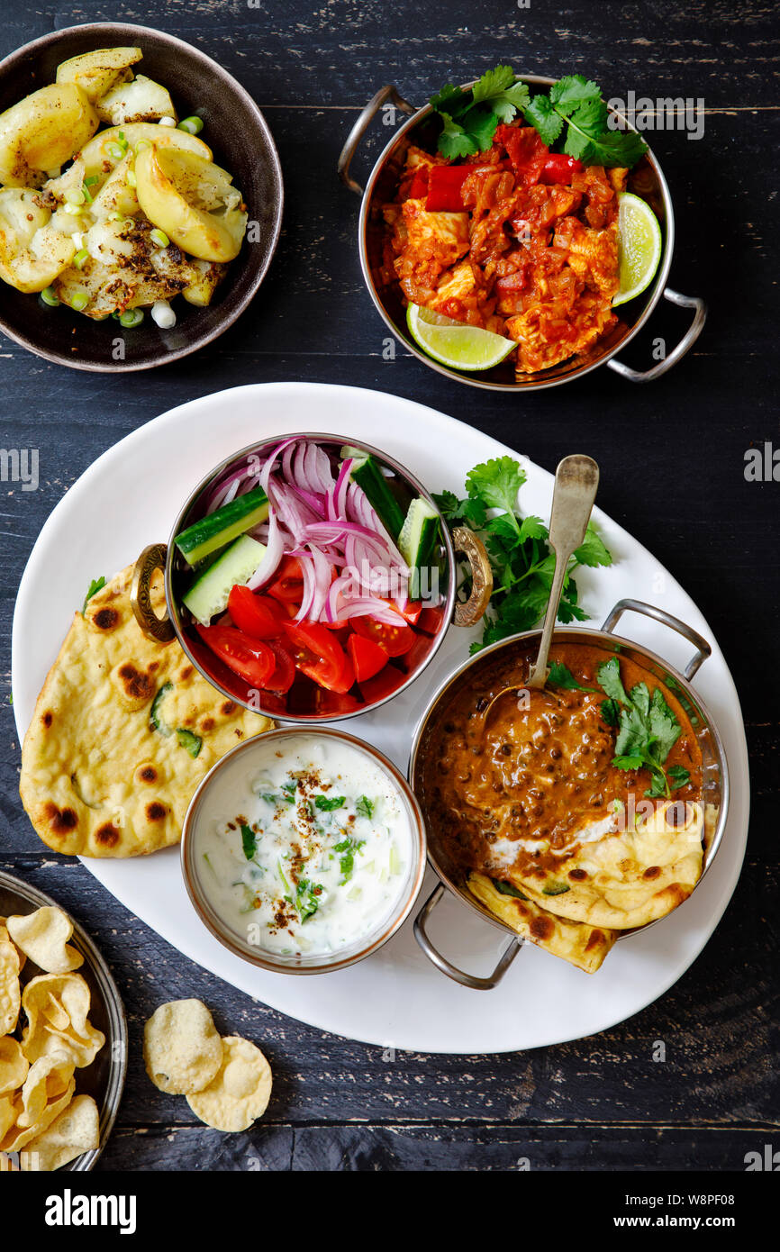 Indian curry meal with black lentils dal, spicy potatoes, rice, naan