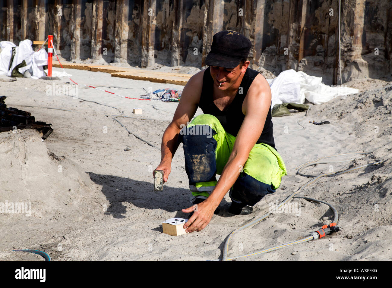 Archaeologist Jeppe Faerch-Jensen, Museum of South-East Denmark, is placing markers in the sand as preparation for drone photography of the large 500 years old ship wreck which has just has been excavated at a building site near Koege, Denmark. (Photo by Ole Jensen/Alamy) Stock Photo