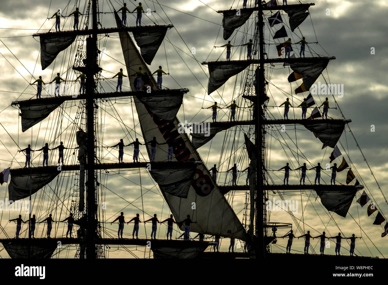 Silhouettes sailors of the Colombian Navy tall ship Gloria standing to attention in salute as the ship arrives for Hanse-sail maritime festival, Rosto Stock Photo