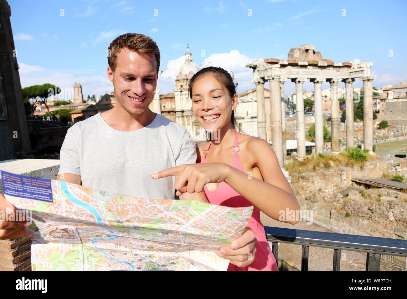 Tourists holding map by Roman Forum sightseeing on travel vacation in Rome, Italy. Happy tourist couple, man and woman traveling on holidays in Europe smiling happy. Interracial Asian Caucasian couple Stock Photo