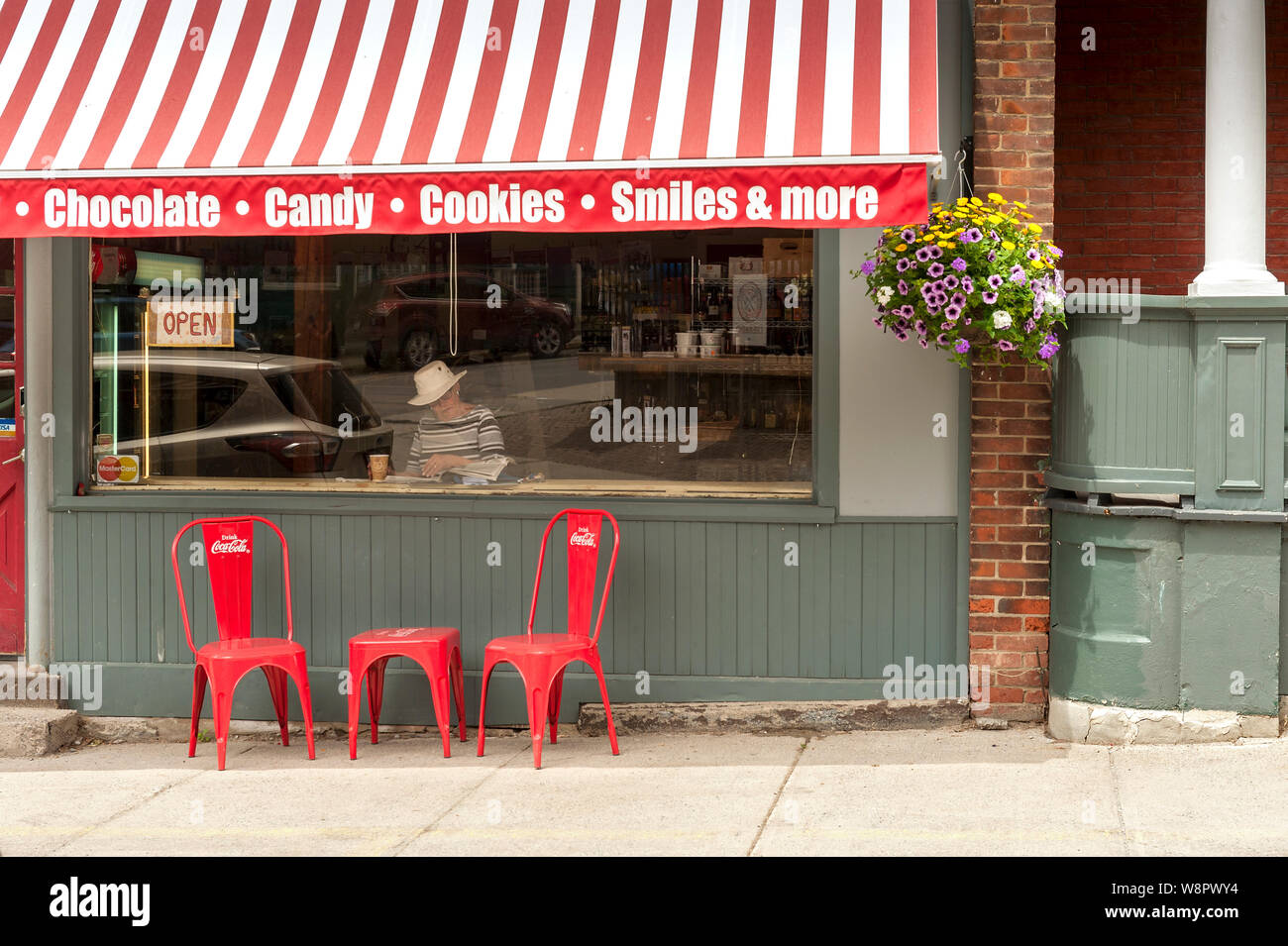 Woman reading in bakery window under red and white awning and sign Stock Photo