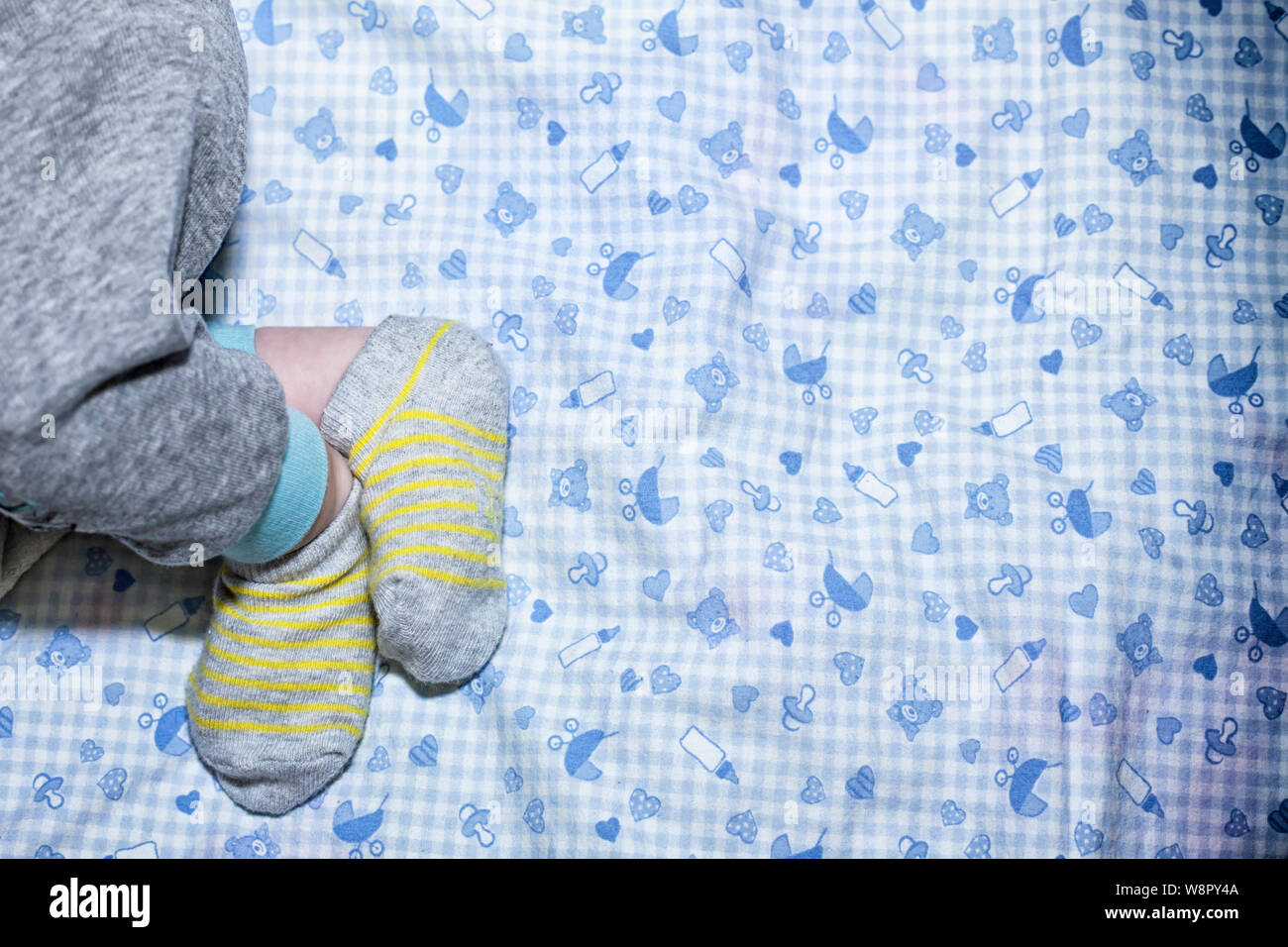 Newborn babies legs. Stocks and pijamas. Blue pattern background. Stock Photo