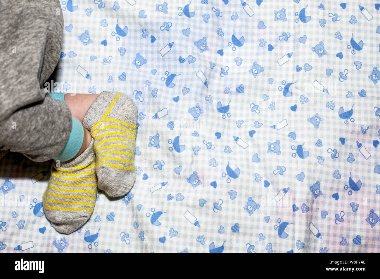 Newborn babies legs. Stocks and pijamas. Blue pattern background. Stock Photo