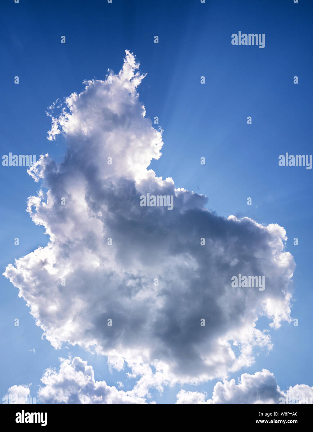 Sun behind clouds against a blue sky. Clouds that block the sun can have a "silver lining Stock