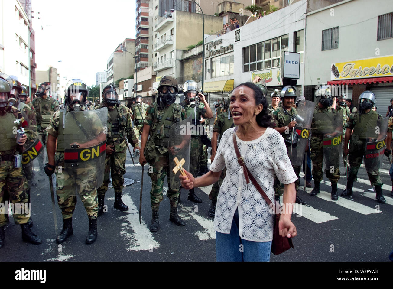 A woman holding a cross shouts in front of national guard soldier during a protest against Venezuelan President Hugo Chavez in Caracas, Venezuela, Nov Stock Photo