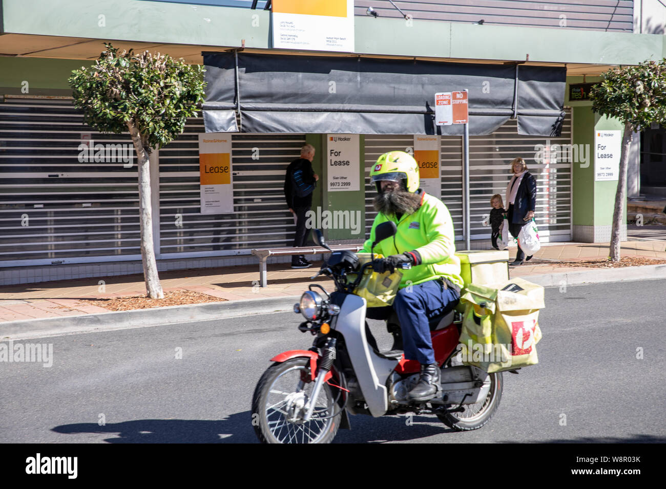 Australian postman postie on iconic Honda super cub motorbike in Sydney,Australia Stock Photo