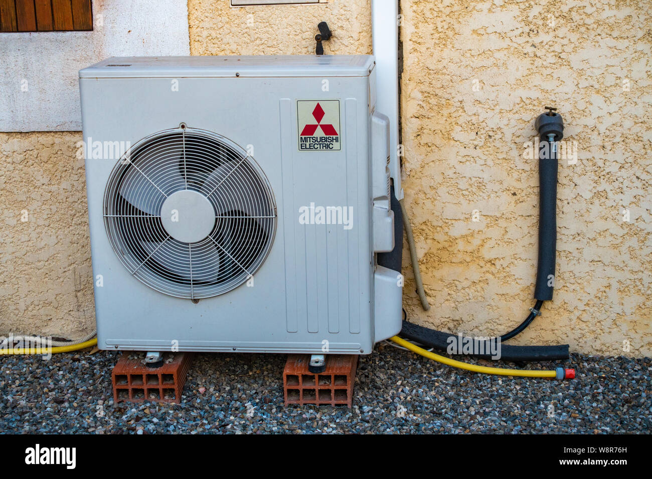 Mitsubishi air conditioning exterior unit standing on 2 bricks Stock Photo  - Alamy