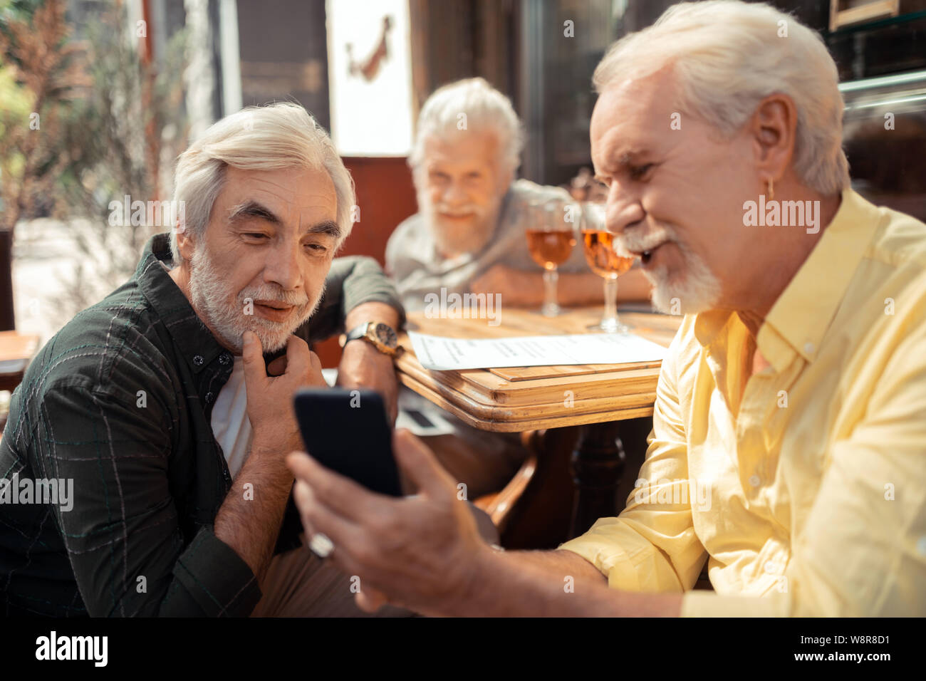 Man showing old photos to his friend while reminding the past Stock ...