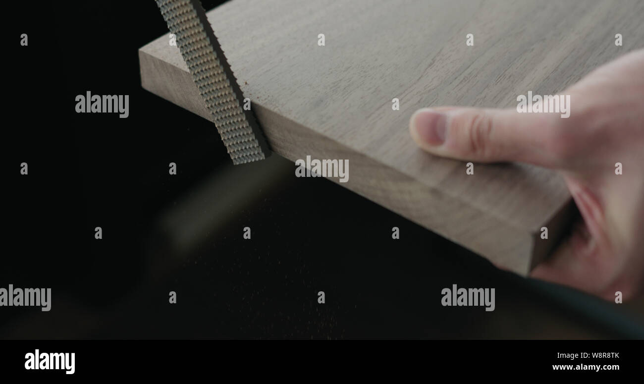 woodworker hand sanding walnut board with file, wide photo Stock Photo