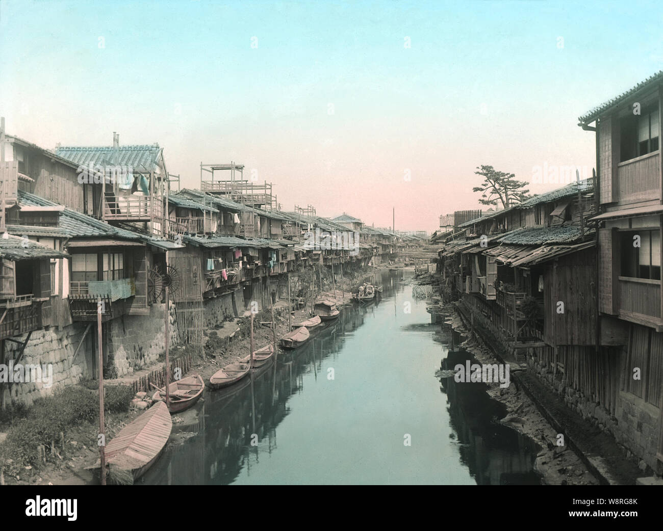 [ 1890s Japan - Canal in Osaka ] —   Kurayashiki and teahouses on the Shijimigawa River in Osaka’s Kitashinchi. Several boats can be seen. A Kurayashiki is a house built like a warehouse. Boats with geisha entertaining guests could be seen here in the evening, laughter and shamisen music drifting into the air.   19th century vintage albumen photograph. Stock Photo