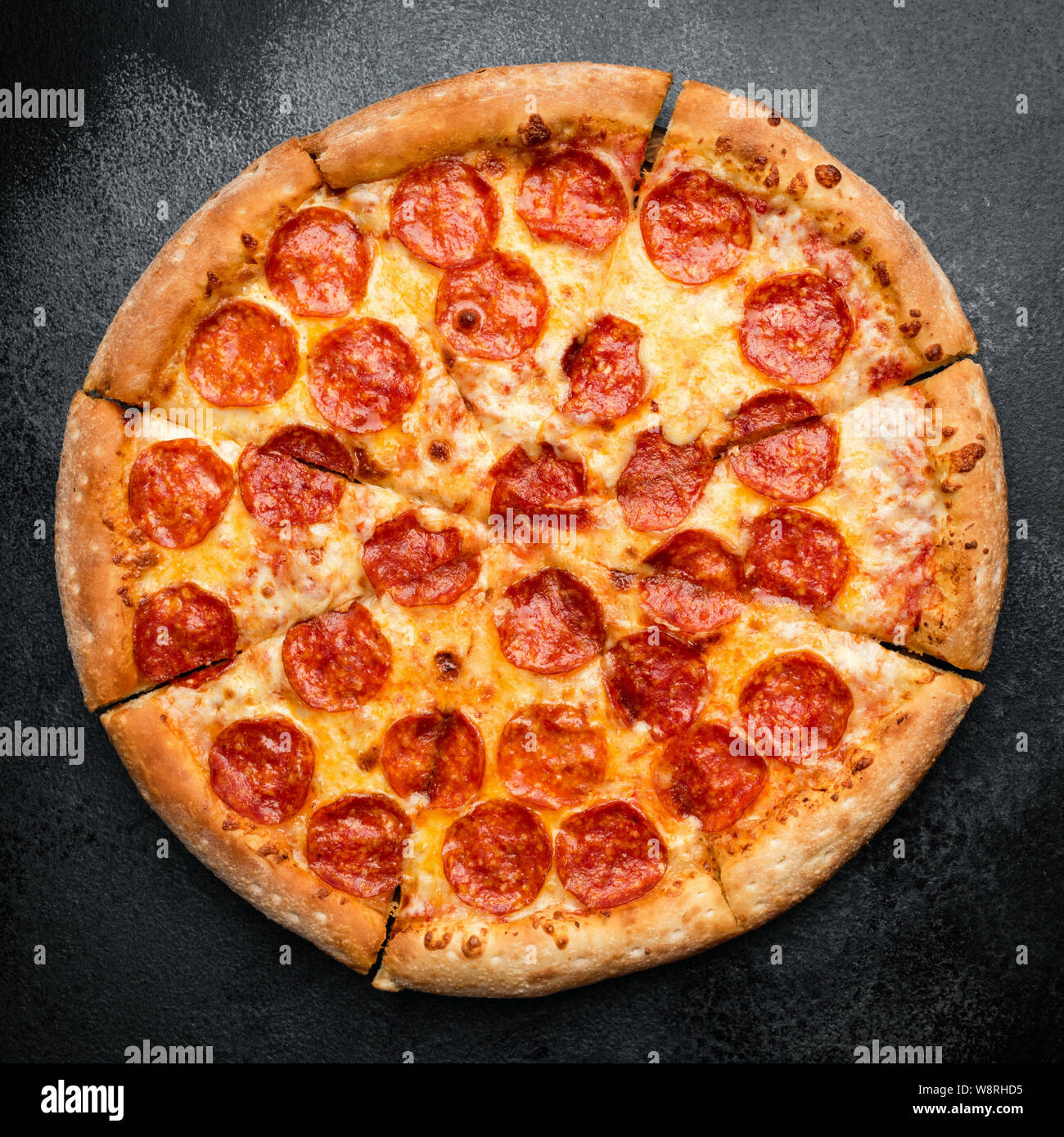 Tasty Pepperoni Pizza Sliced On Black Concrete Background. Table Top View. Fast Food Stock Photo
