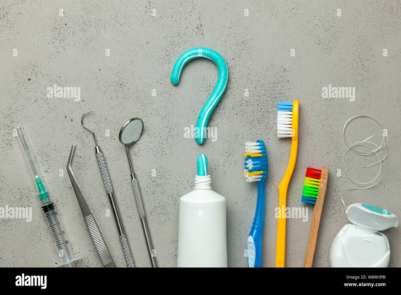 Toothpaste in the form of a question mark and many different and colored toothbrushes and dental
