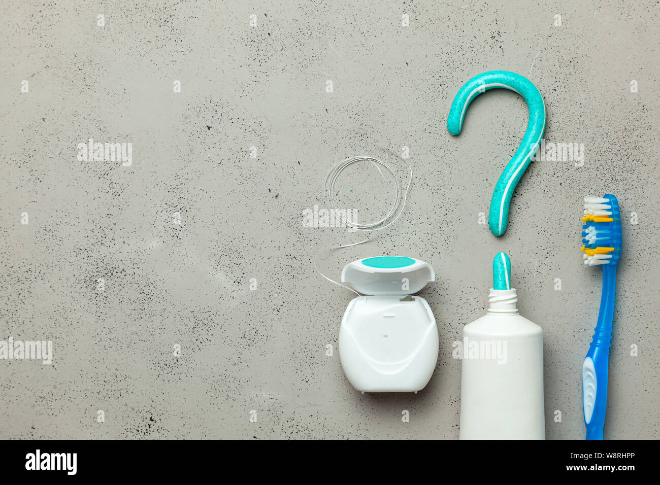 Toothpaste in the form of a question mark and toothbrushes and dental floss. Concept of how to