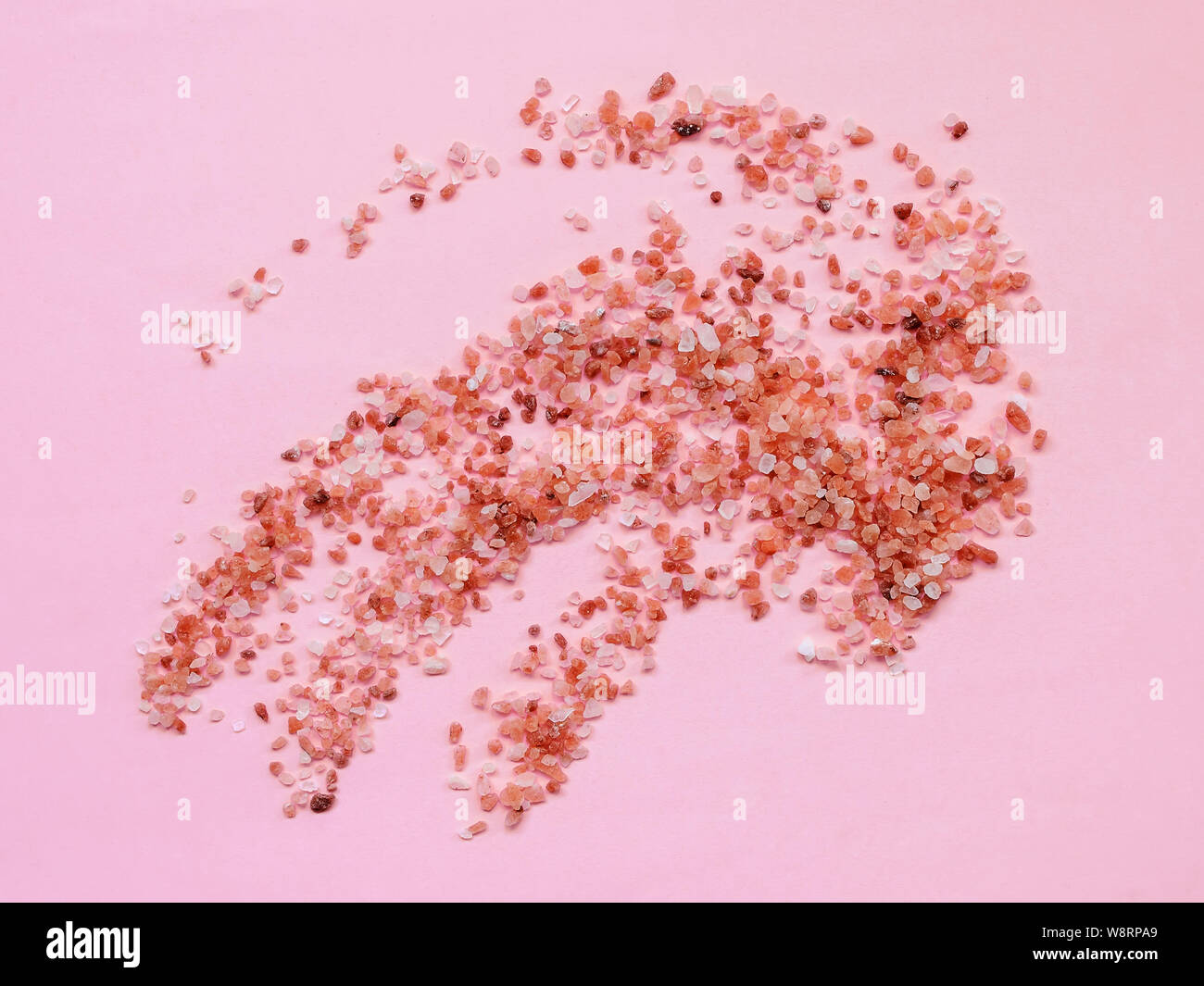 Scattering of pink himalayan salt crystals on a pastel pink background ...