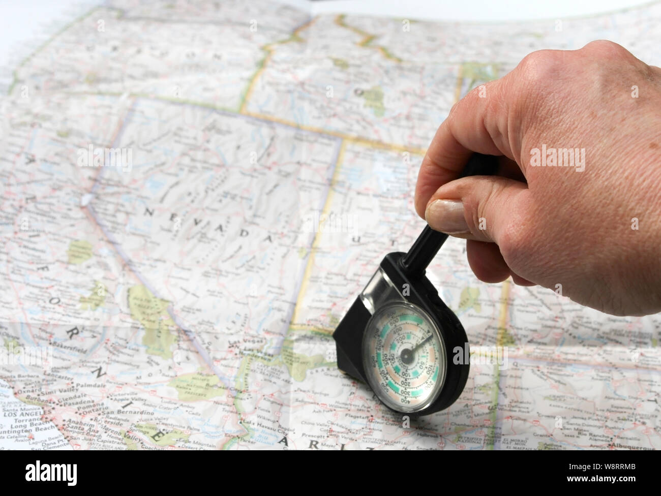 Hand with distance calculator on route map of west usa Stock Photo - Alamy