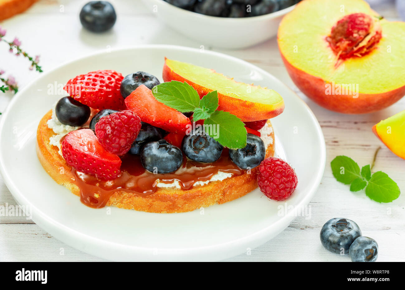 Delicious breakfast. Delicacy sandwich Toasts with cream cheese or mascarpone, caramel (iris toffee) and fresh berries - blueberries, raspberries, str Stock Photo