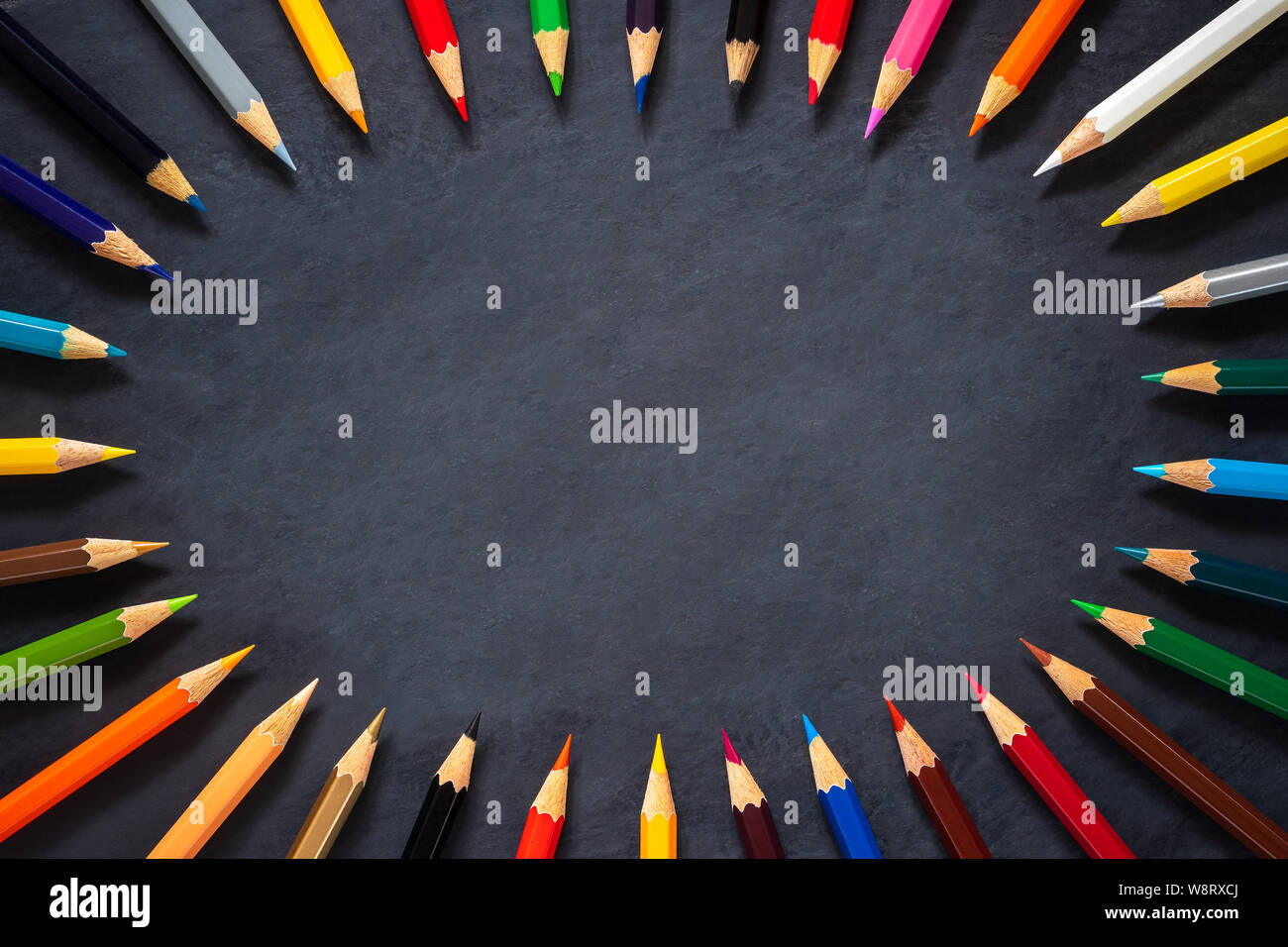 Colored pencils on chalkboard background. Top view and copy space