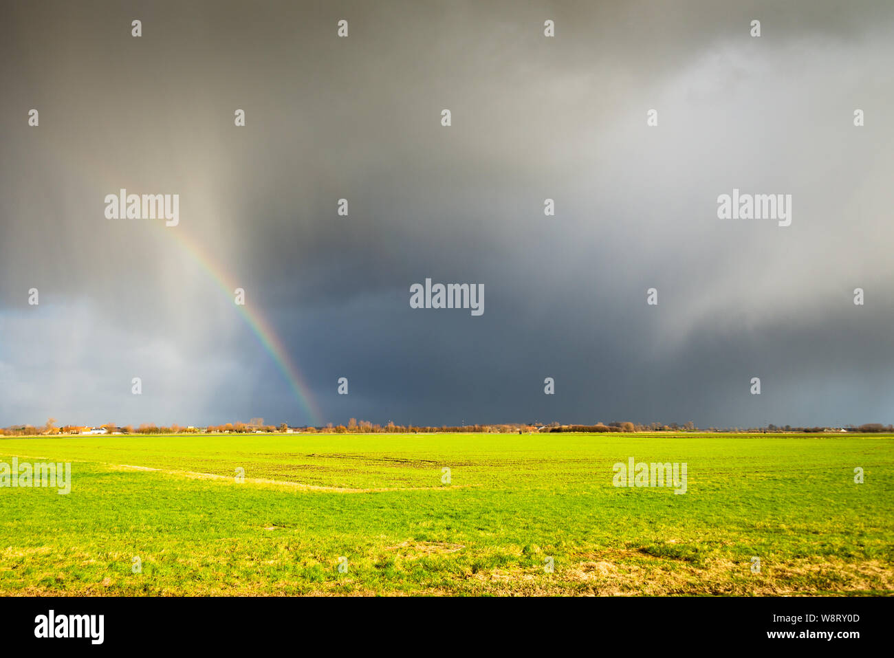 A beautiful rainbow and dark clouds after a thunderstorm. Stock Photo