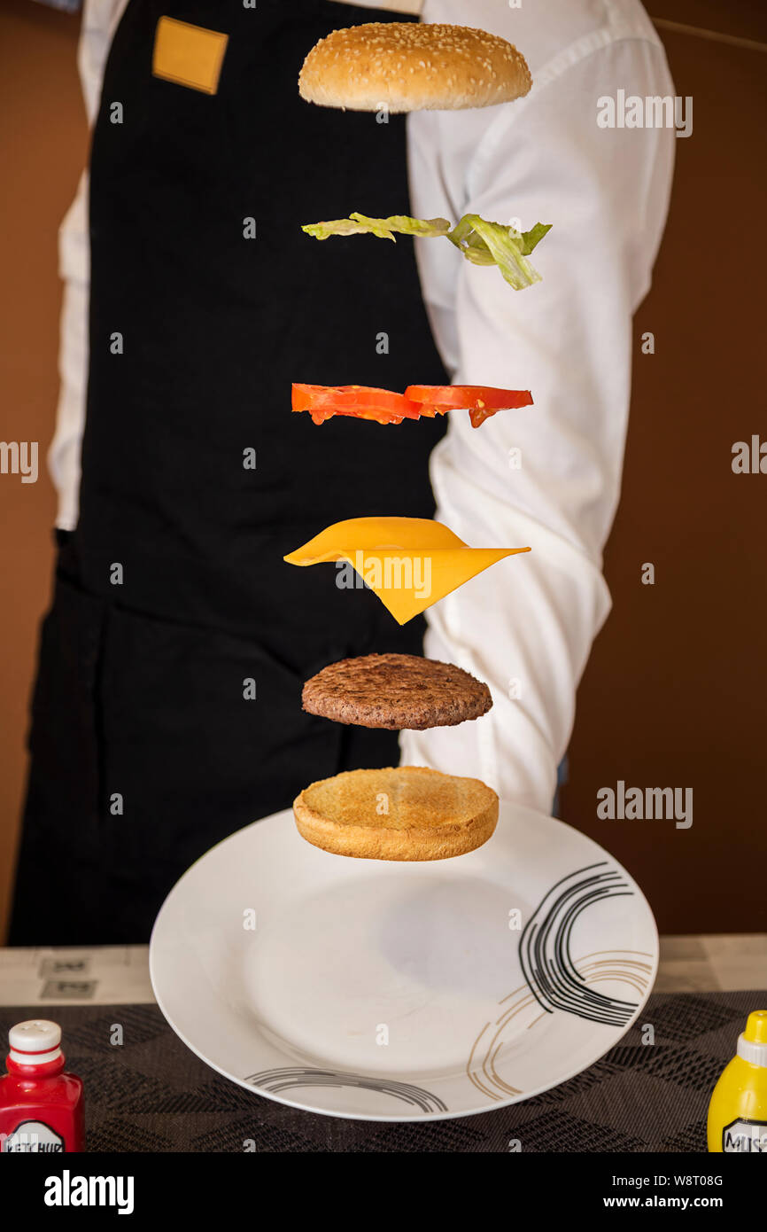 Waiter serving a flying hamburger Stock Photo