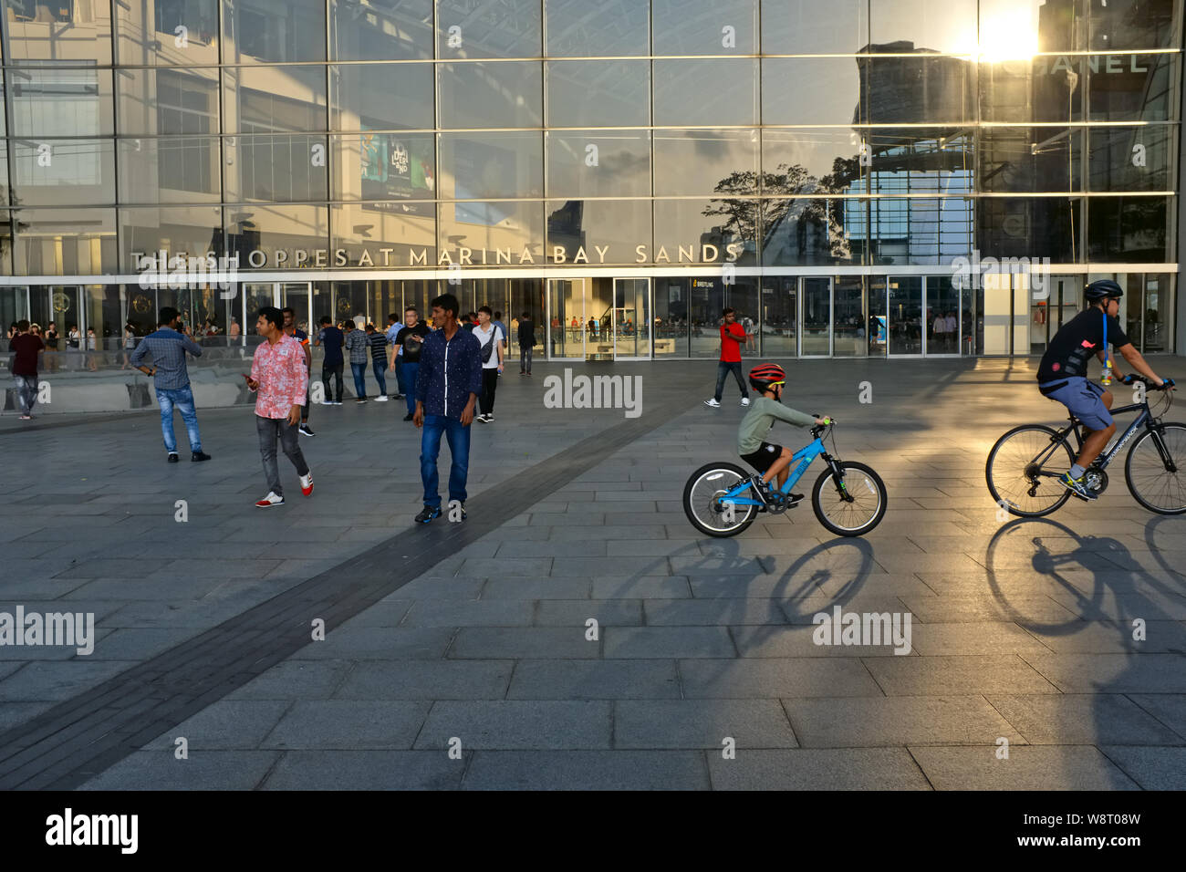 Cyclists passing The Shoppes At Marina Bay Sands, a luxury shopping mall attached to Marina Bay Sands Hotel, at the Event Plaza, Marina Bay, Singapore Stock Photo